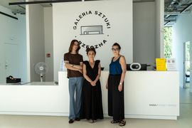 Zdjęcie przedstawia trójkę osób pozujących do zdjęcia w Galerii Sztuki. 