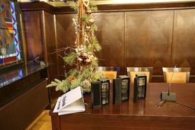 Statuetki i dyplomy nagród miasta w dziedzinie kultury na tle bożonarodzeniowej dekoracji w sali sesyjnej Rady Miasta Rybnika