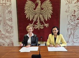 Zdjęcie przedstawia dwie kobiety siedzące przy biurku. 