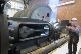 Zabytkowa kopalnia - elementy dawnej parowej maszyny wyciągowej szybu. Obok mężczyzna z telefonem.