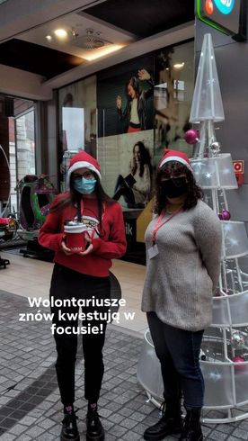 Dwie dziewczyny w czapkach Mikołaja w holu galerii handlowej