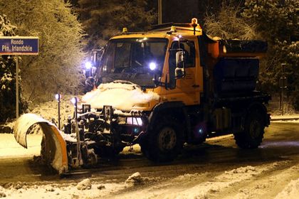 Pługopiaskarka odśnieżająca ulicę. Wieczór.