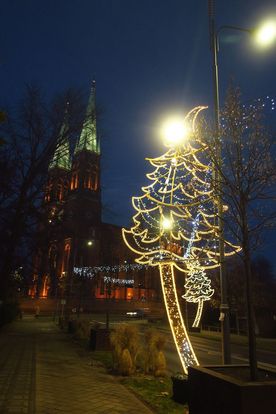 Świecące o zmierzchu świąteczne dekoracje miasta - choinka, karuzela, girlandy nad ulicą