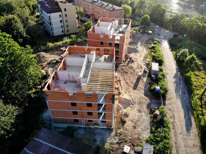 Budynki wielorodzinne w trakcie budowy. W tle istniejąca zabudowa i zieleń.