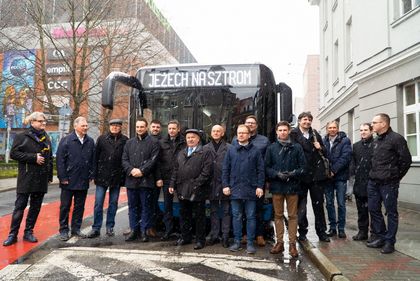 Grupa mężczyzn pozująca do zdjęcia na tle autobusu