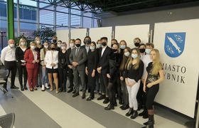 Grupa młodzieży pozuje do zdjęcia na tle planszy z herbem Rybnika