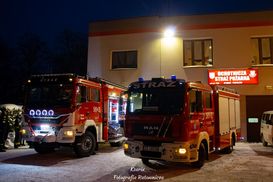 Dwa wozy strażackie przed komendą OSP w zimowej scenerii