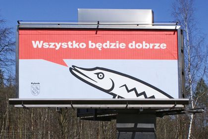 Bilbord cov1 2 Bilbord na tle błękitnego nieba i drzew.