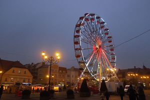 Podświetlona karuzela typu diabelski młyn, stojąca o zmierzchu na rynku miejskim. 