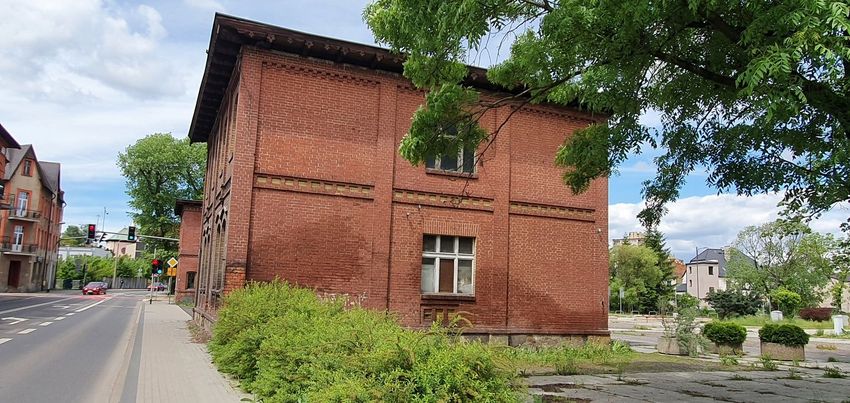 Ceglany budynek przy ulicy, zieleń, błękitne niebo. 