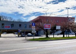 Budynek hali sportowej, na pierwszym planie czerwona tablica z napisem Rybnicki Punkt Szczepień