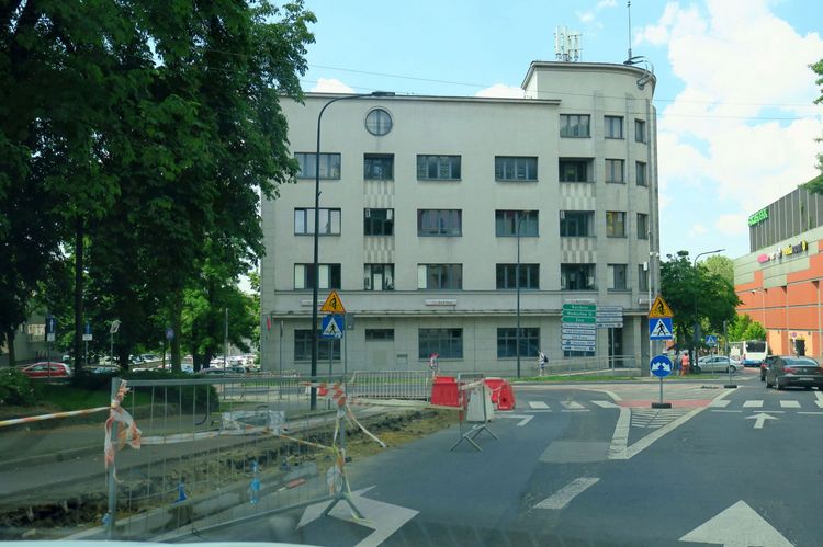 Ulica w rejonie skrzyżowania, w trakcie robót drogowych. W tle kilkupiętorwy budynek 