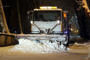 Pługopiaskarka odśnieżająca ulicę. Wieczór.