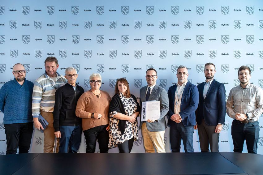 Dziewięć osób stojących na tle ścanki promocyjnej miasta 