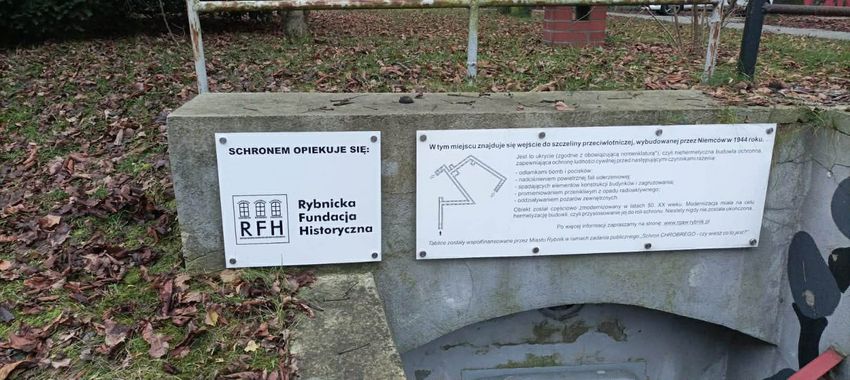 zdjęcie tabliczki Rybnickie Fundacji Historycznej na tle schronu