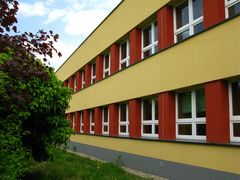 Piętrowy budynek szkolny, w otoczeniu drzew