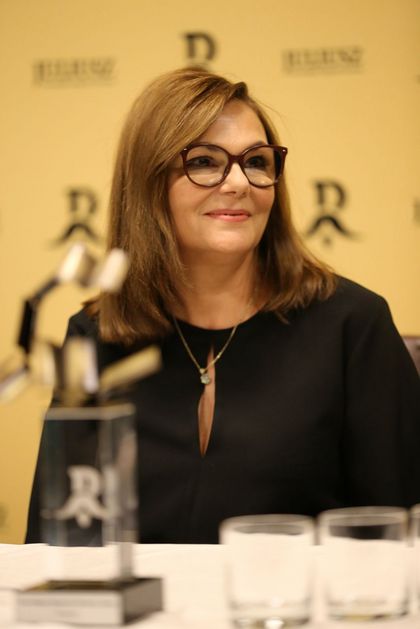 Laureatka Nagrody Literackiej Juliusz Marta Grzywacz ze statuetką nagrody na żółtym tle z logotypem nagrody Juliusz. 
