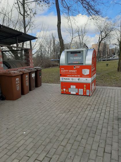 Czerwony kontener na odpady elektryczne, elektrośmieci. Obok inne kontenery na odpady