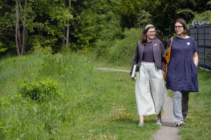Zdjęcie przedstawia dwie kobiety spacerujące w lesie.