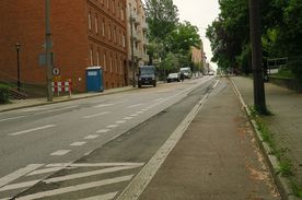 Fragment zniszczonej ulicy z wyznaczoną ścieżką rowerową 