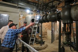 Zabytkowa kopalnia - elementy dawnej parowej maszyny wyciągowej szybu, w tle trzech mężczyzn