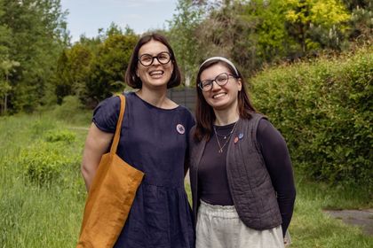 Zdjęcie przedstawia dwie kobiety spacerujące w lesie.