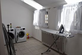 Jasne wnętrze z akcesoriami domowymi, w tym pralką, suszarką i żelazkiem