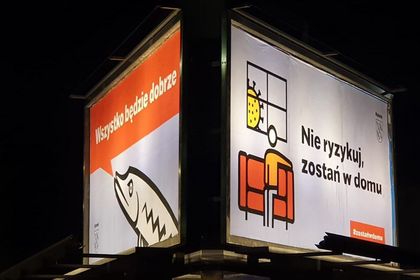 Bilboard Nocne zdjęcie bilbordu z grafikami - szczupakiem i człowiekiem na domowej kanapie