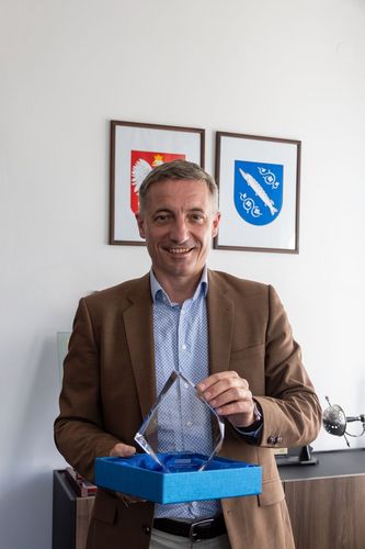 Zdjęcie przedstawia mężczyznę pozującego do zdjęcia ze statuetką.