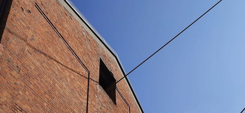 Fragment budynku z cegły na tle błękitnego nieba
