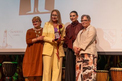 Cztery kobiety pozują do zdjęcia na scenie.