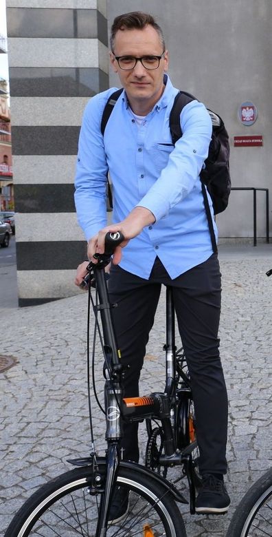 Mężczyna w niebieskiej koszuli stojący przy rowerze