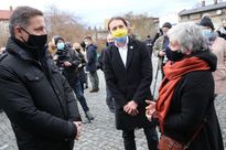 Kilka osób na otwartej przestrzeni. Na pierwszym planie dwóch mężczyzn i kobieta w maseczkach. 