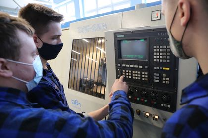 Trzech mężczyzn testujących sprzęty elektroniczne w nowocześnie wyposażonej pracowni kształcenia zawodowego 
