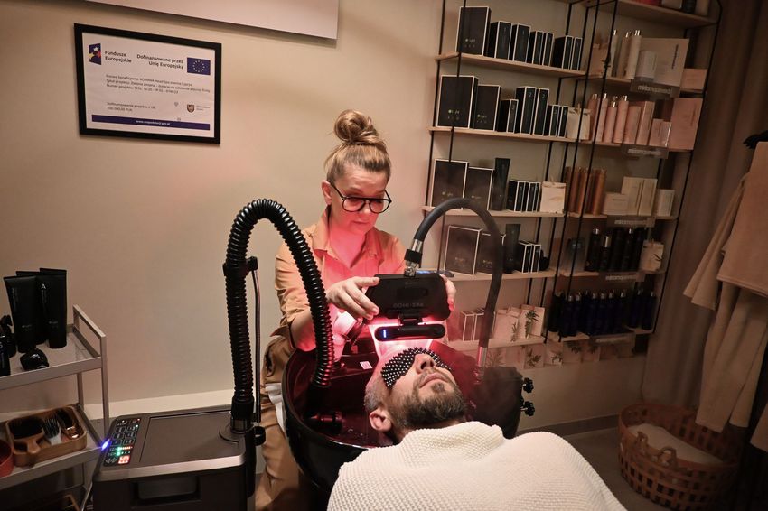 Zdjęcie przedstawia siedzącą kobietę oraz leżącego mężczyznę w salonie SPA.