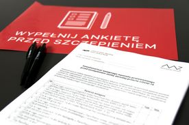 Leżąca na stole karta z wzorem deklaracji do wypełnienie. Obok kilka długopisów i czerwona tabliczka