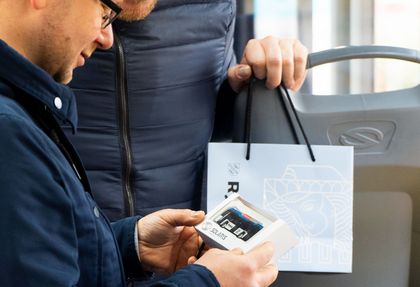 Osoba trzymająca gadżet w kształcie miejskiego autobusu