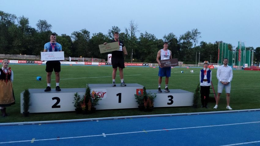 Zdjęcie przedstawia pięć osób pozujących do zdjęcia. Trójka osób stoi na podium.