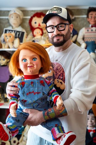Zdjęcie przedstawia mężczyznę trzymającego w rękach lalkę Chucky.