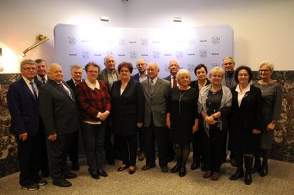 Grupa seniorów - kobiet i mężczyzn stojących w półkolu