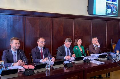 Grupa ludzi siedzących przy stole w sali w urzędzie miasta.