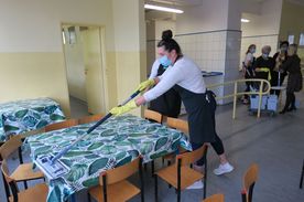 Kobieta myjąca mopem stoli na szkolnej stołówce