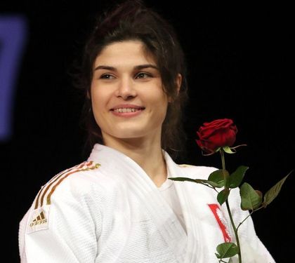 Kobieta w stroju judoki. W ręce trzyma czerwoną różę.
