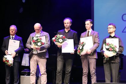 Pięć osób z kwiatami i dyplomami.