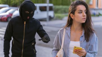 kobieta z telefonem, mężczyzna z tyłu w kominiarce