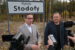 Dwóch mężczyzn na tle tablicy z napisem Rybnik-Stodoły