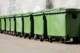 Stojące w rzędzie kontenery na odpady komunalne