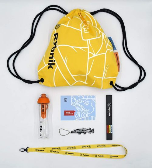 Rybnicka wyprawka pierwszoklasisty: żółty plecaczek, bidon na wodę, komplet ołówków, smycz, breloczek w kształcie szczupaka i kartka życzeniami prezydenta