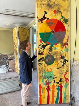 Zdjęcie zastępcy prezydenta obok kolorowej ściany w remontowanym budynku