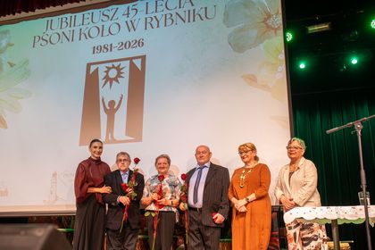 Grupa osób pozuje do zdjęcia na scenie.